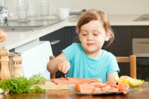 Ребенок на кухне готовит рыбу
