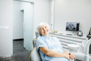Портрет пожилой женщины в стоматологическом кабинете. Пациентка задумалась о стоимости имплантации в Санкт-Петербурге